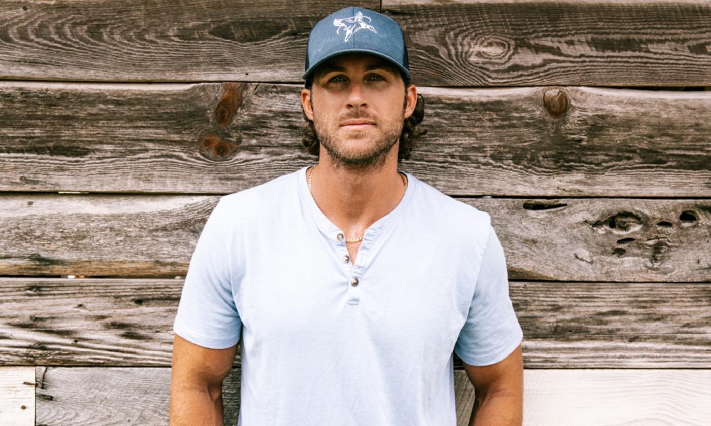 Riley Green poses in front of a wood backdrop