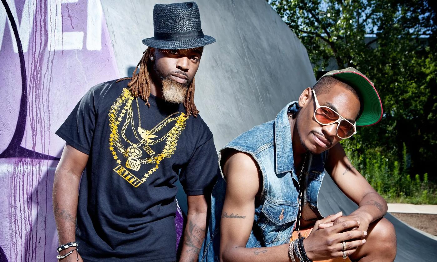 The Ying Yang Twins lean on a large purple skateboard ramp. Kaine is on the left and D-Roc is on the right as they both pose 