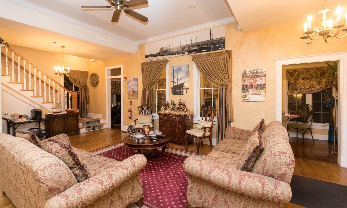 The warm, welcoming living room area, with hand painted gold-tone walls, and comfy sofas at Centennial House B n B in St Augustine