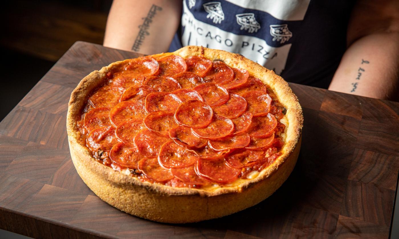 Deep dish pizza is positioned on a small table. 