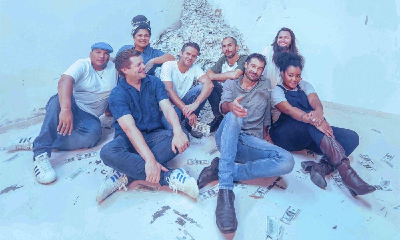 Members of the Cat Empire smile and pose in front of a blue background.
