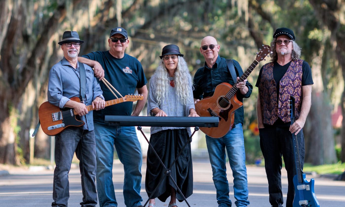 The five-person group, John Dickie and the Collapsible B, standing on Magnolia St. in St. Augustine, holding their instruments or drum sticks