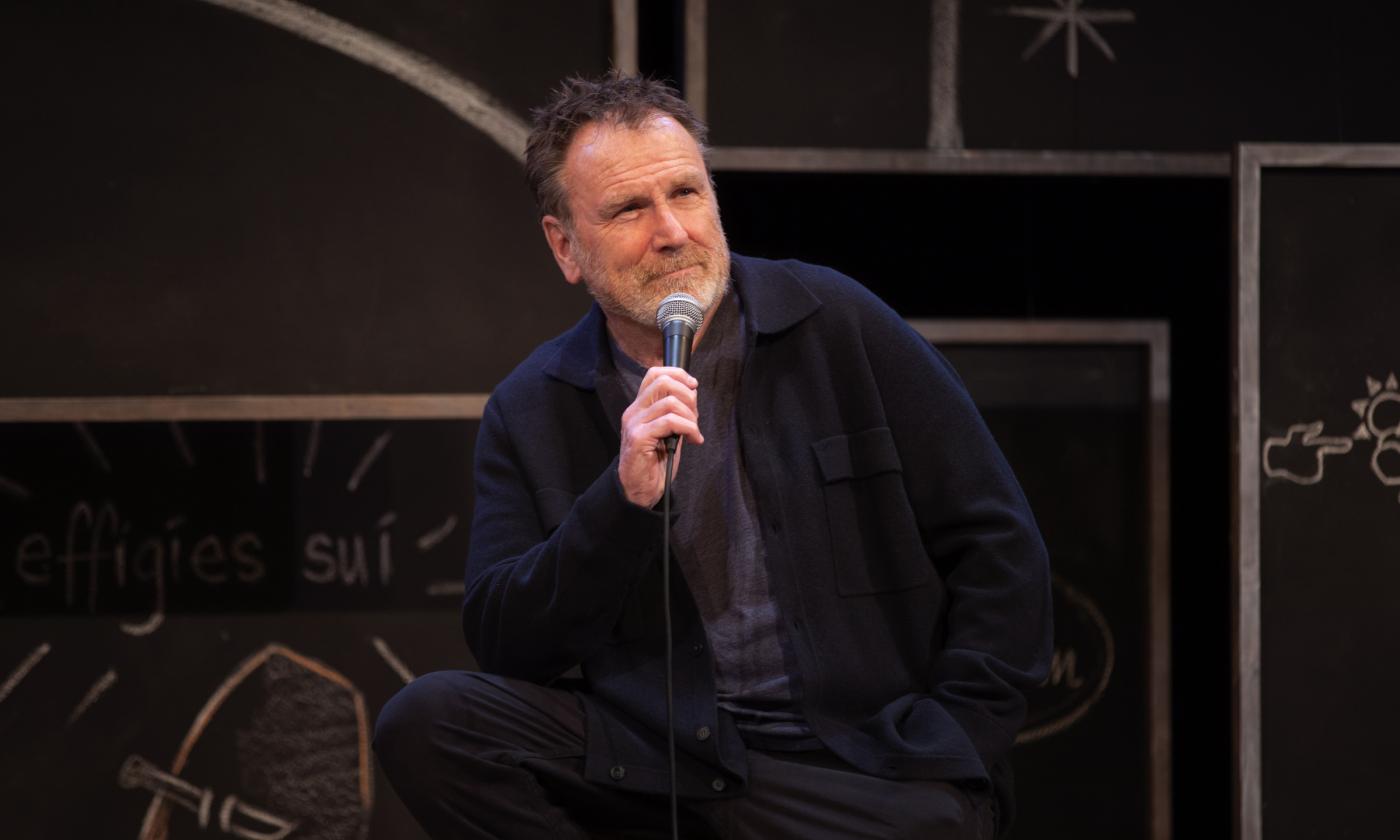 Colin Quinn speaks to fans on stage. 