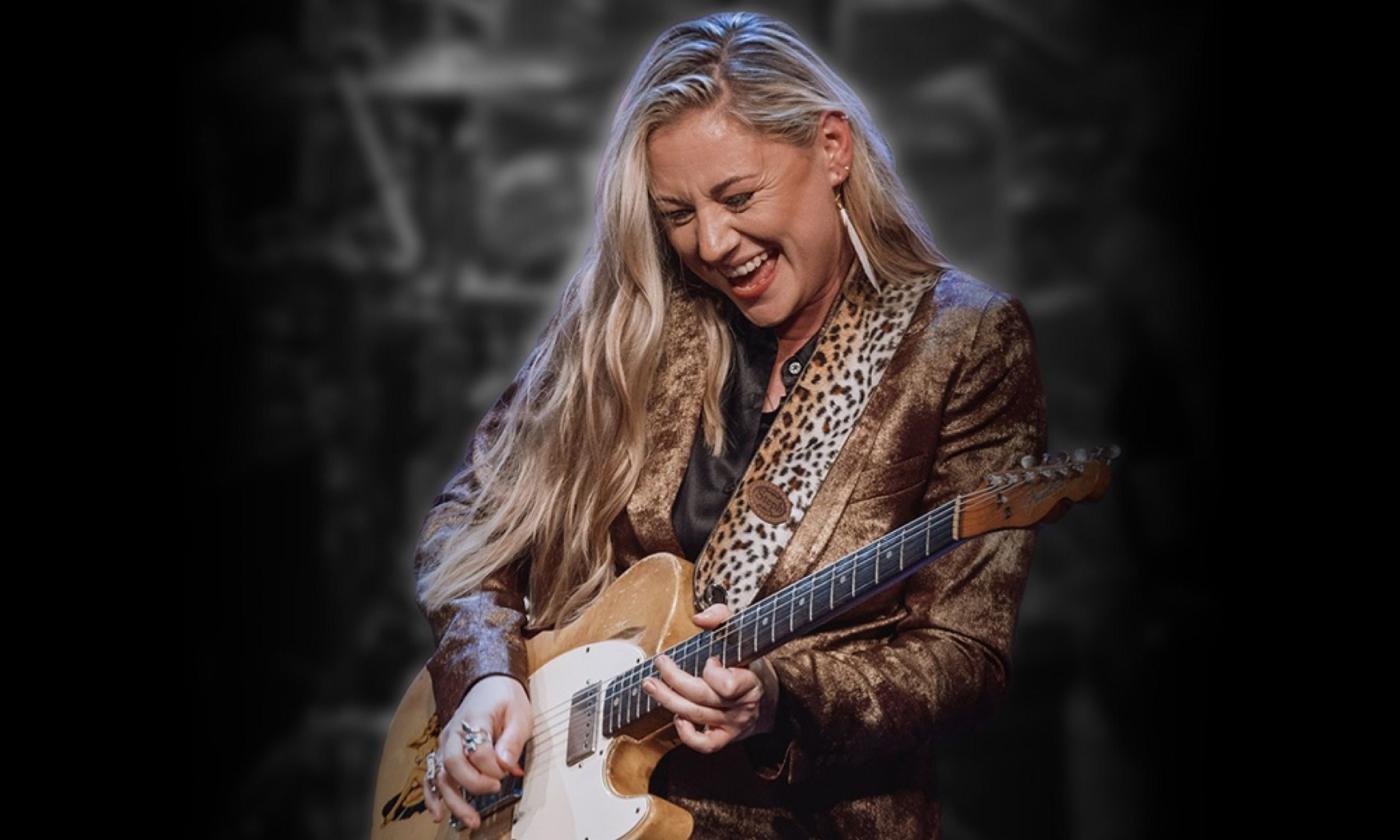 Joanne Shaw Taylor smiles and strums her guitar. 