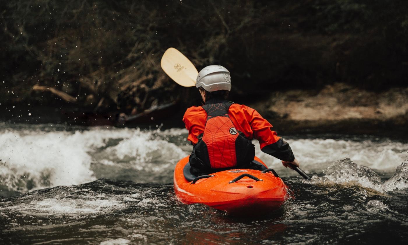 A person uses a paddle to wade through water. 