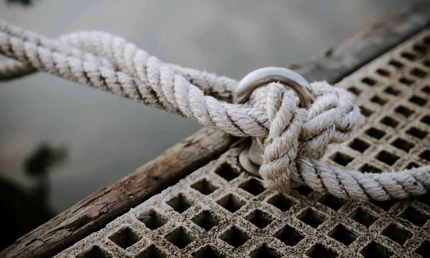 A knot is connected from a deck to a boat. 