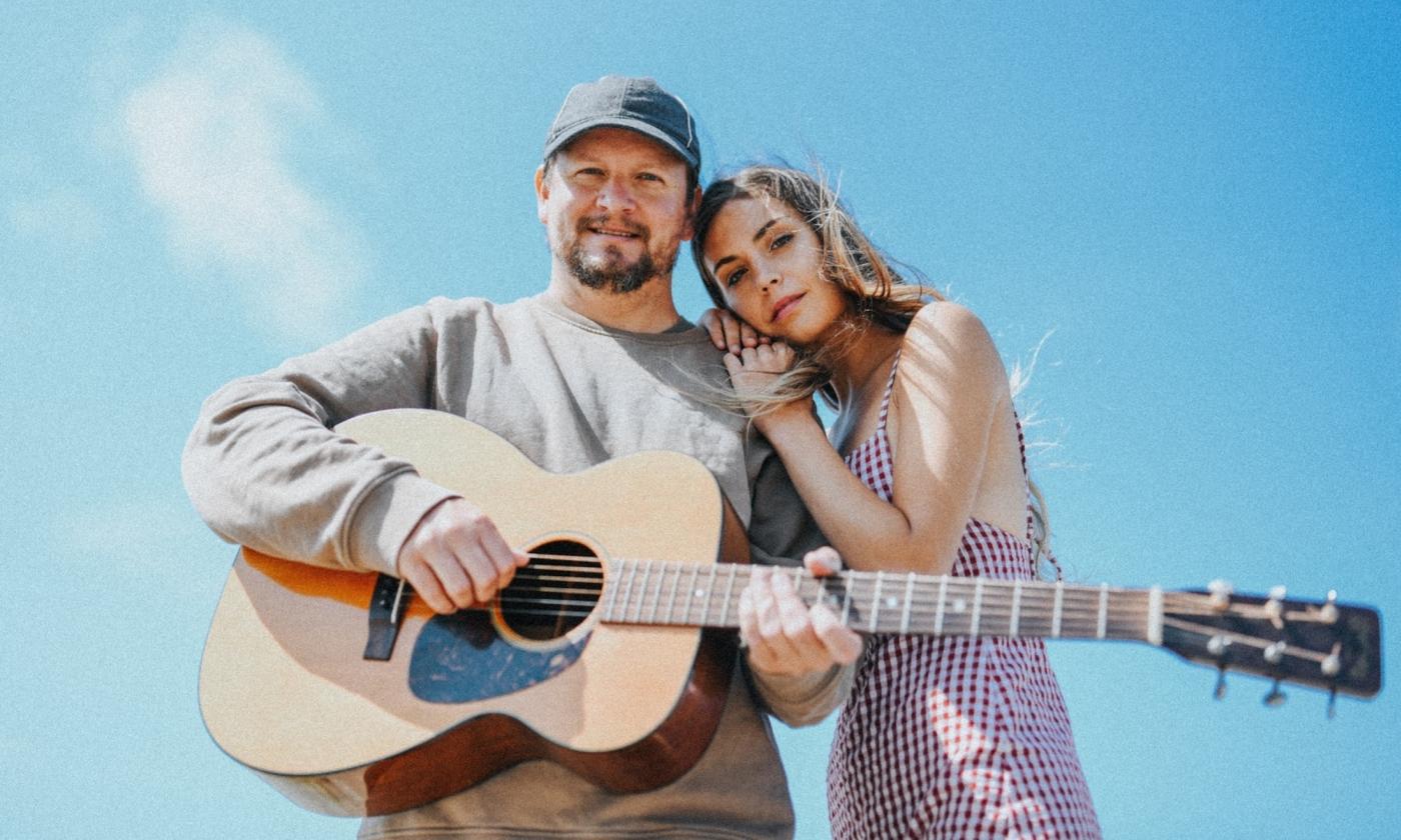 Ocie Elliott smiles and poses with a guitar.