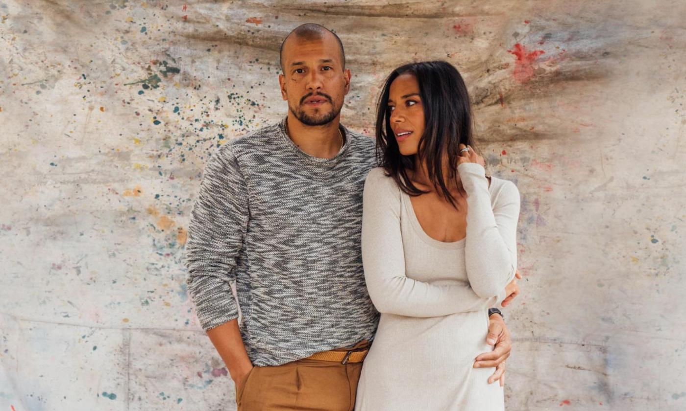 The duo from the band Johnnyswim pose in front of a textured wall.