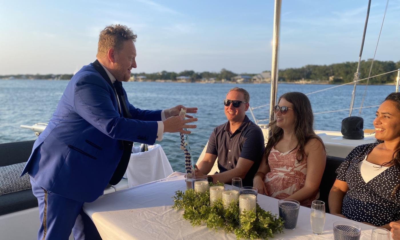 Master magician Bill Abbott performs his act on a sailing catamaran with a small audience