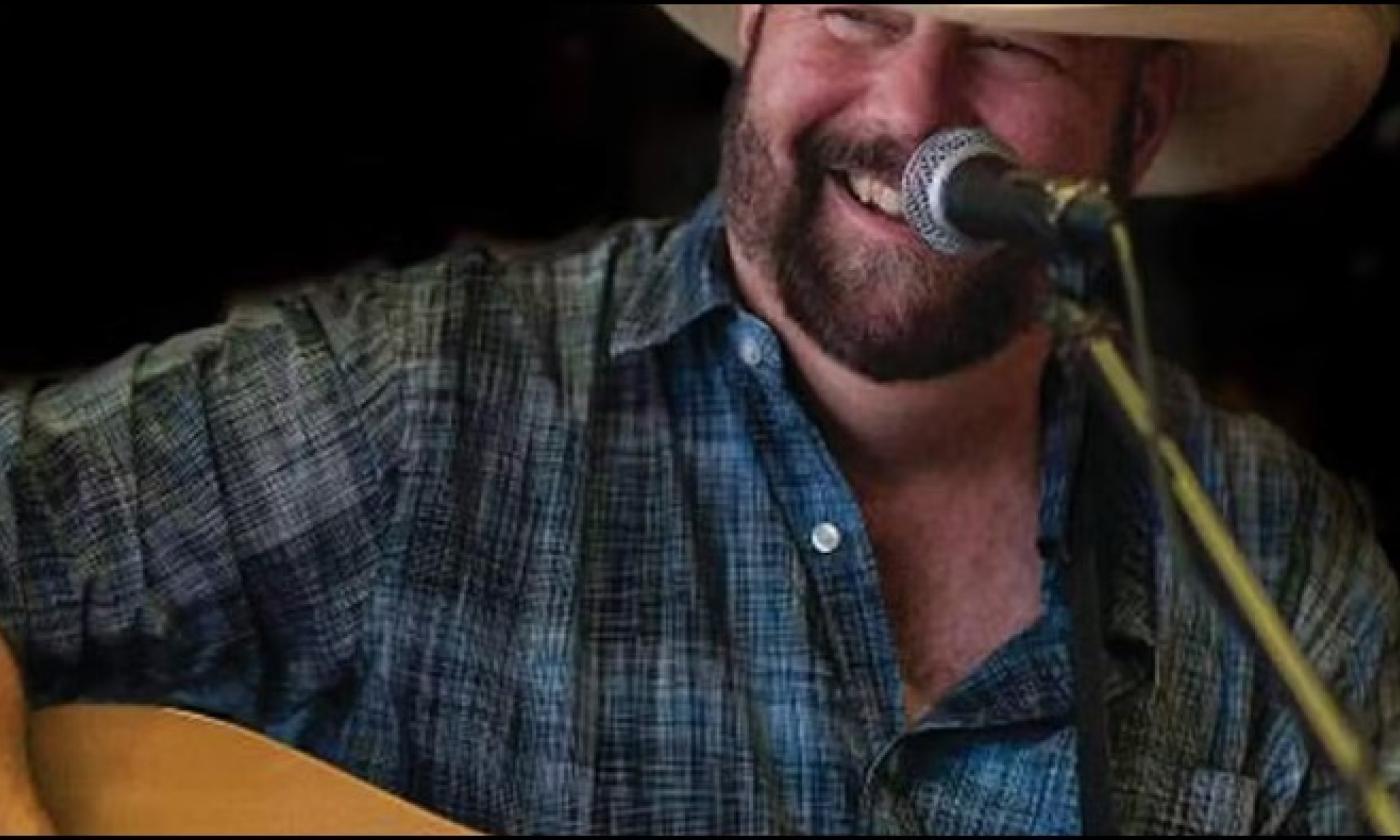 St. Augustine musician FLod Kiser smiling and playing his guitar