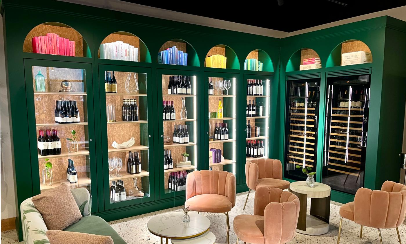 The wine library at Pesca has plush seating and a dark green, glass-fronted wine cellar