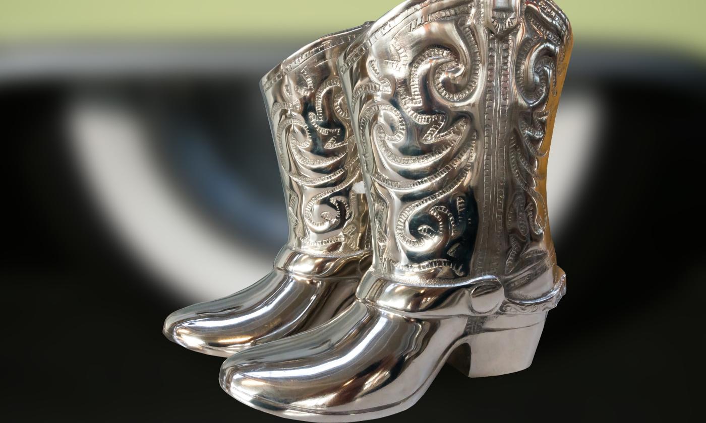 A pair of silver cowboy boots on a multi-colored background
