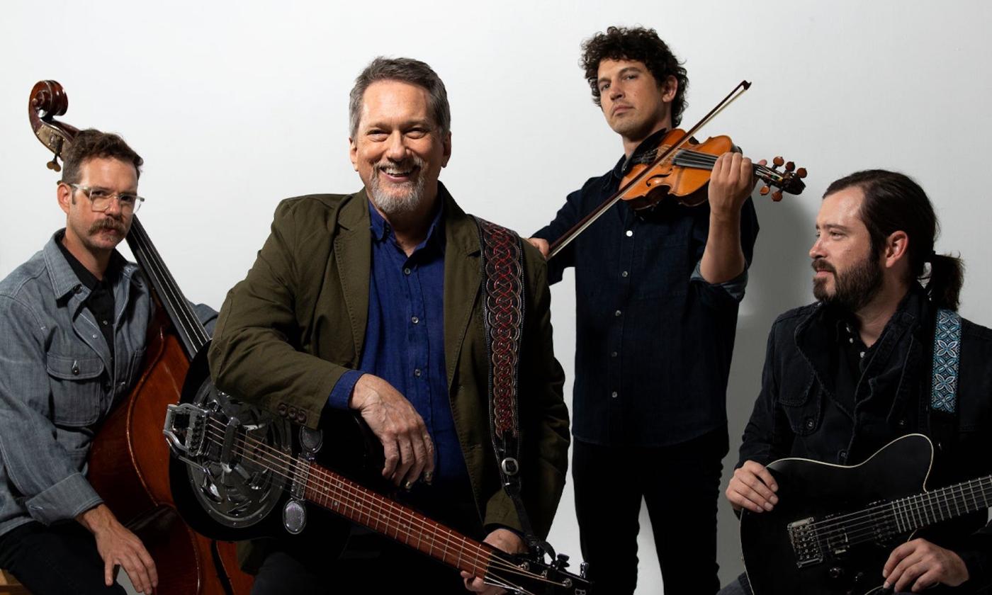 Members of the Jerry Douglas Band smile while holding their musical instruments.