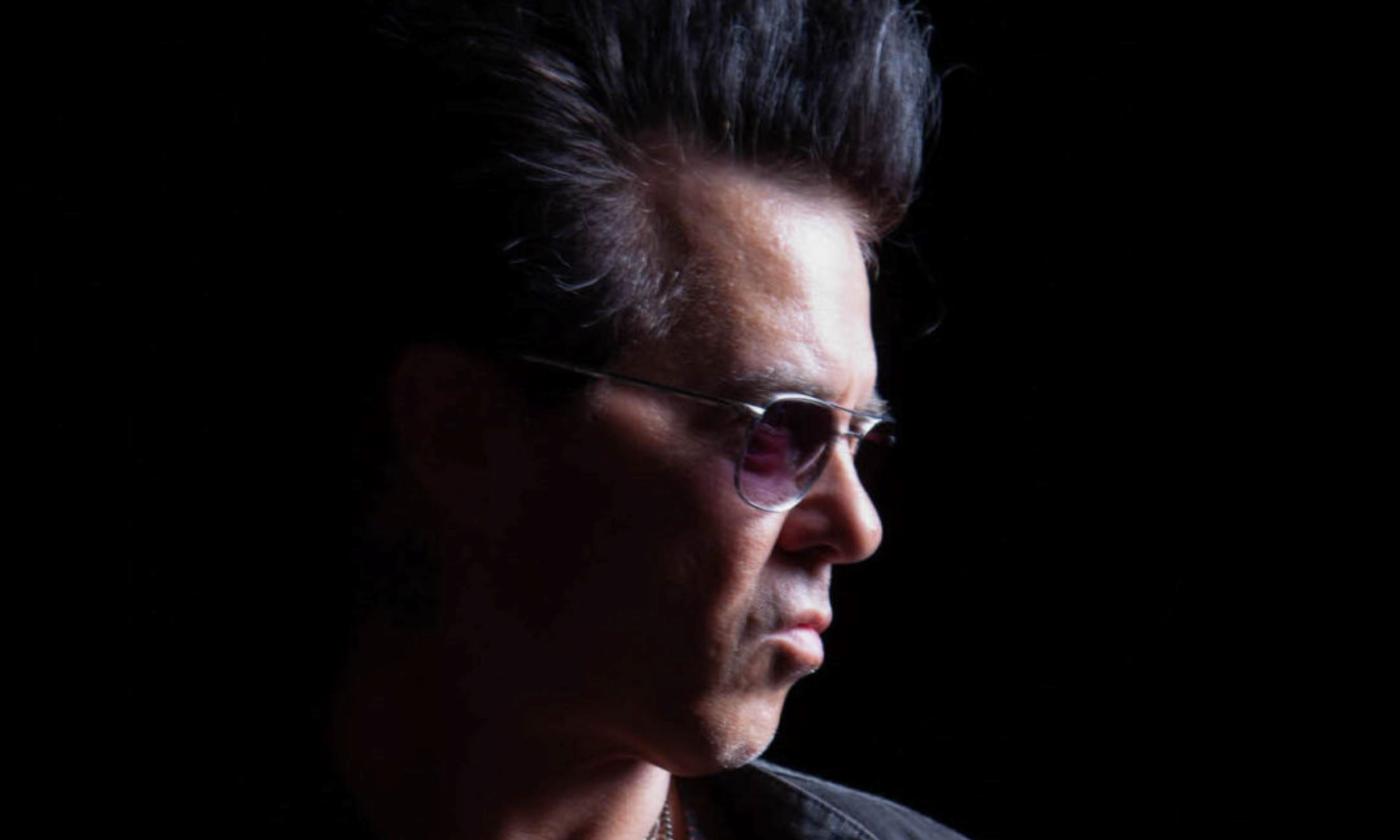 Mike Farris wears glasses while posing in front of a black background. 