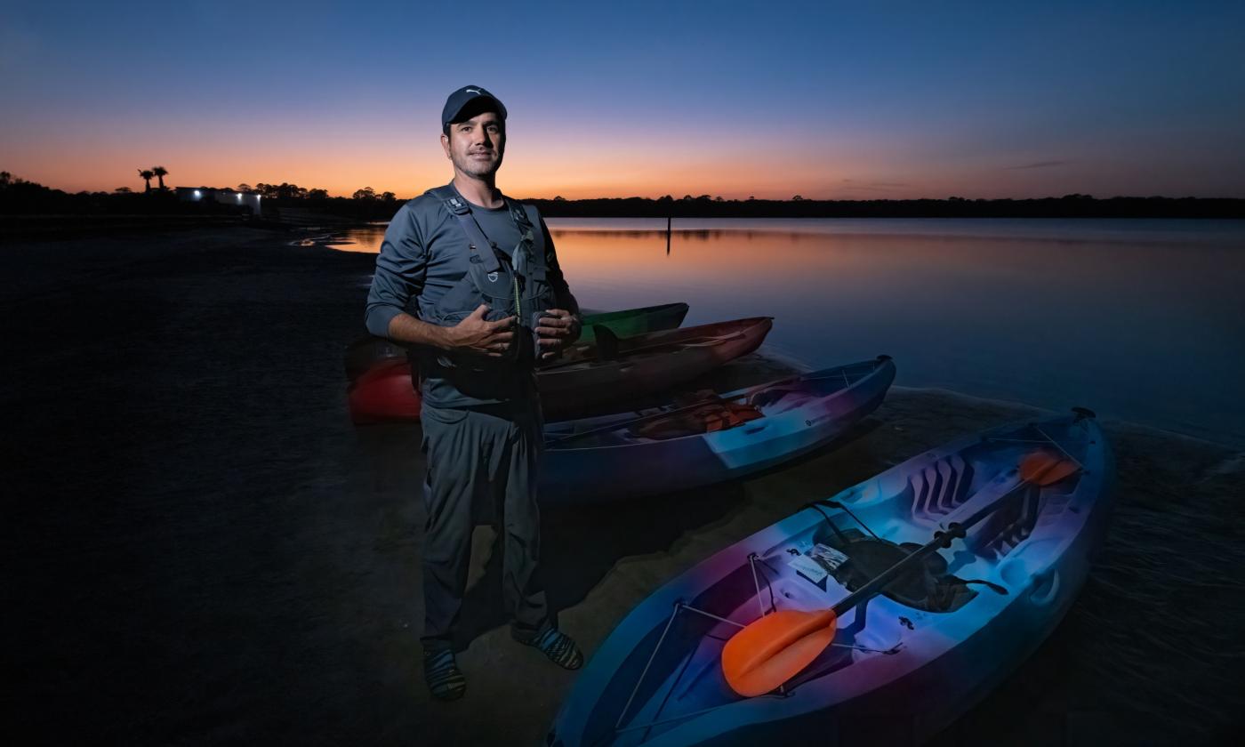 Ben Brandao, owner of GeoTrippin' standing next to kayaks at sunset