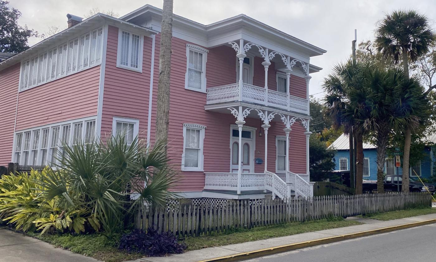 A pink colored house surrounded by palm tree shrubbery