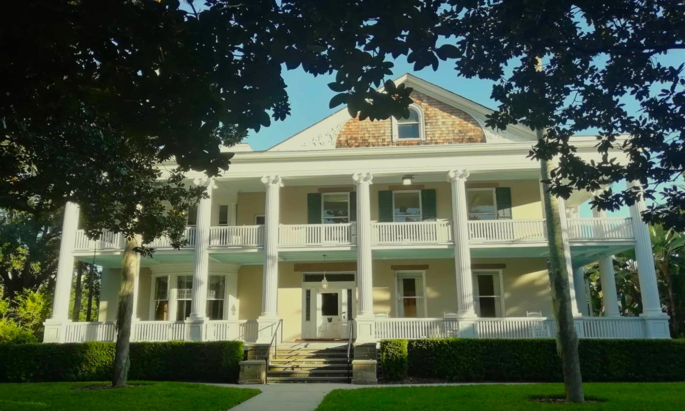 The exterior of the Markland House against a blue sky framed by trees in the yard