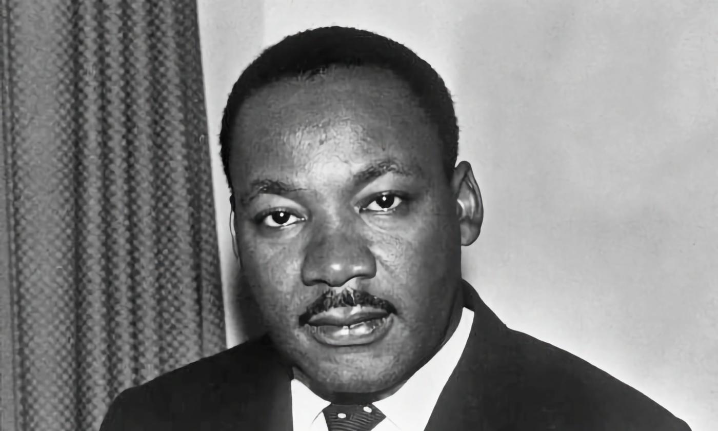 Shoulders-up B&W portrait of Dr. King gazing into the camera.