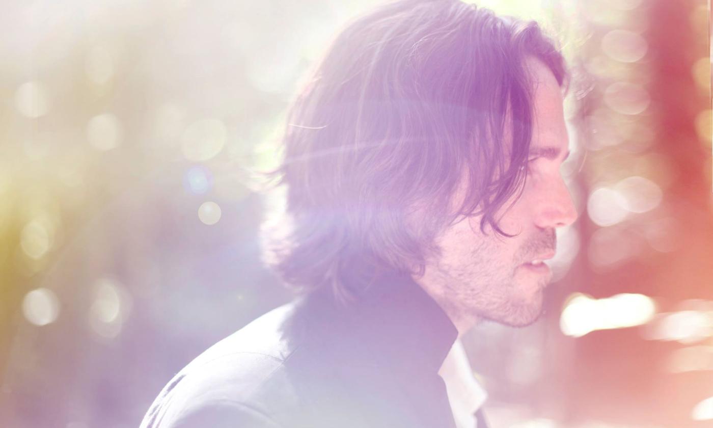 Bokeh and light covers Peter Bradley's Adam's shoulder length hair and face.