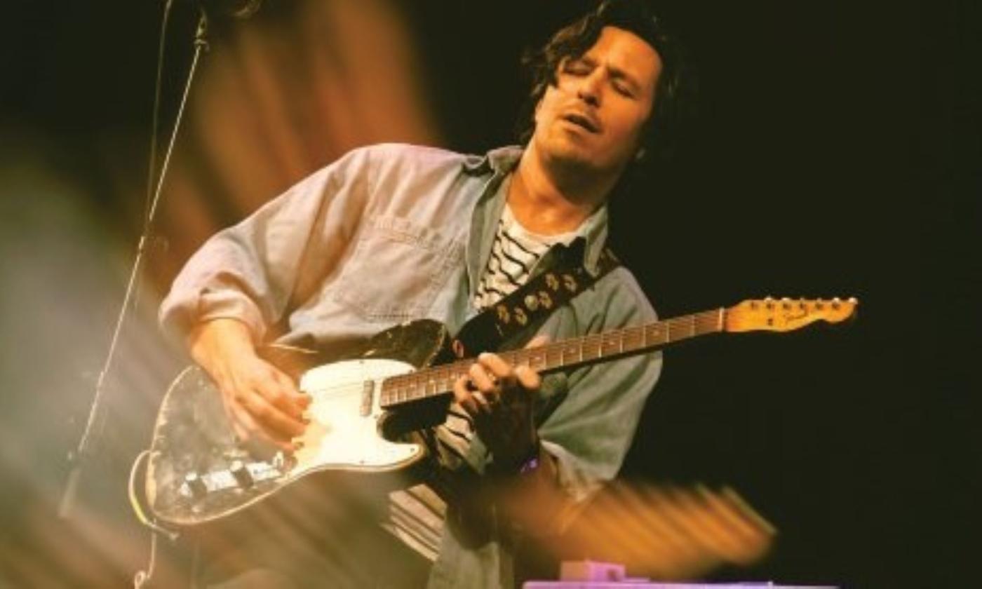 Davy Knowles clutches his guitar and sings to audiences in front of a black backdrop.