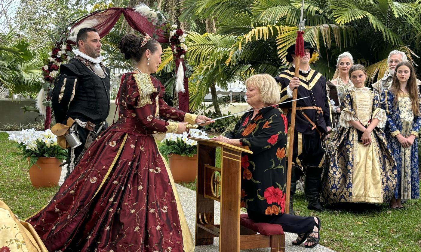 An honoree receiving a sword-to-shoulder knighting from the Queen