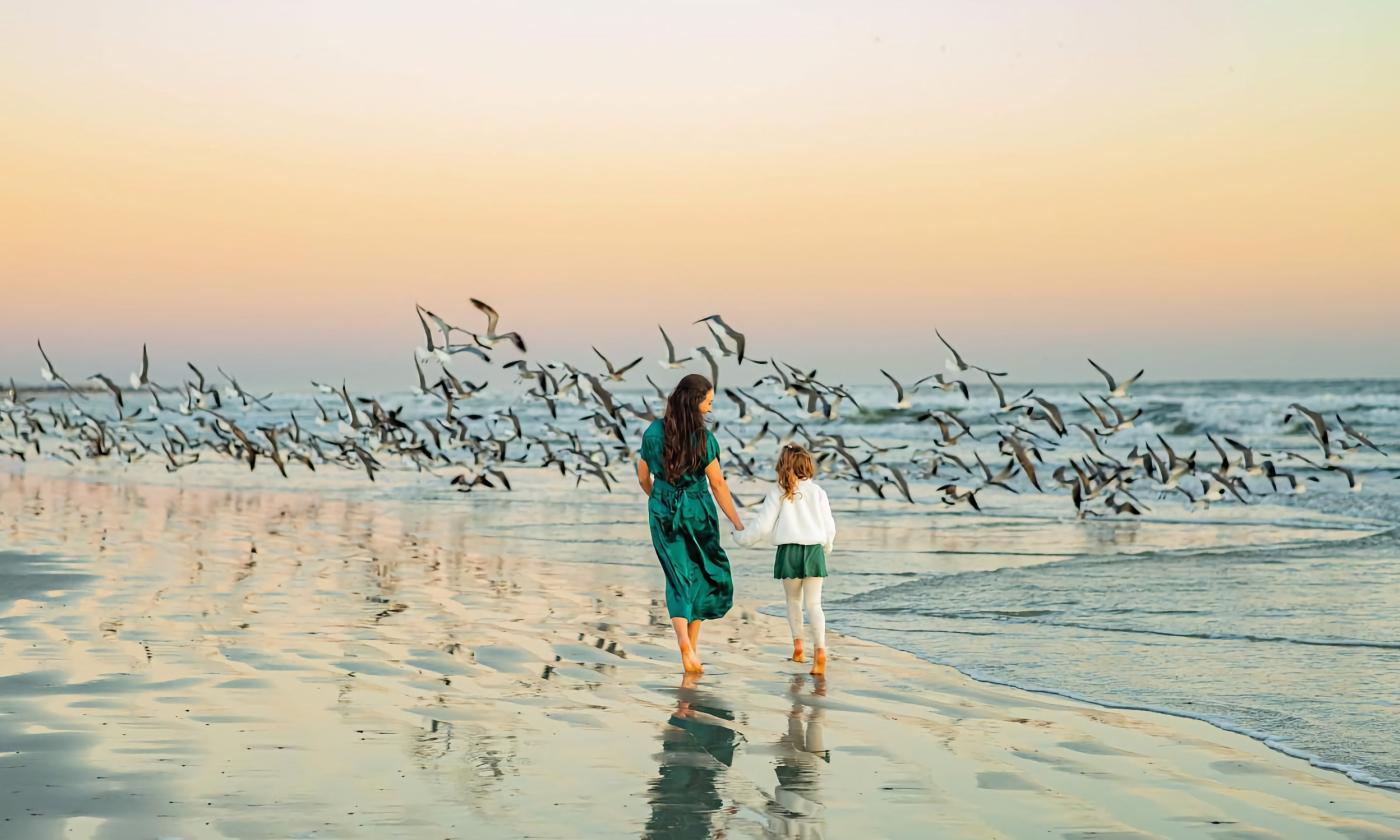 A mother and daughter walking on the beach