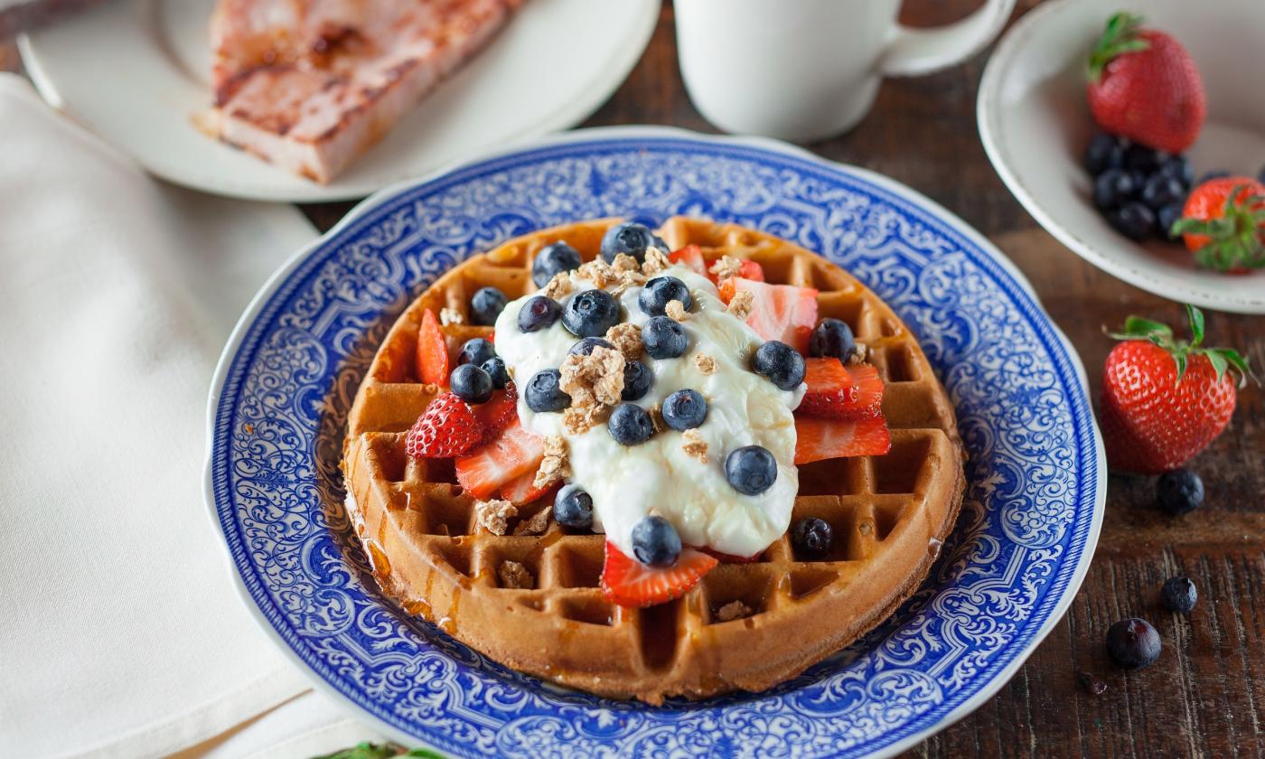 A plated waffle with yogurt and berries on top