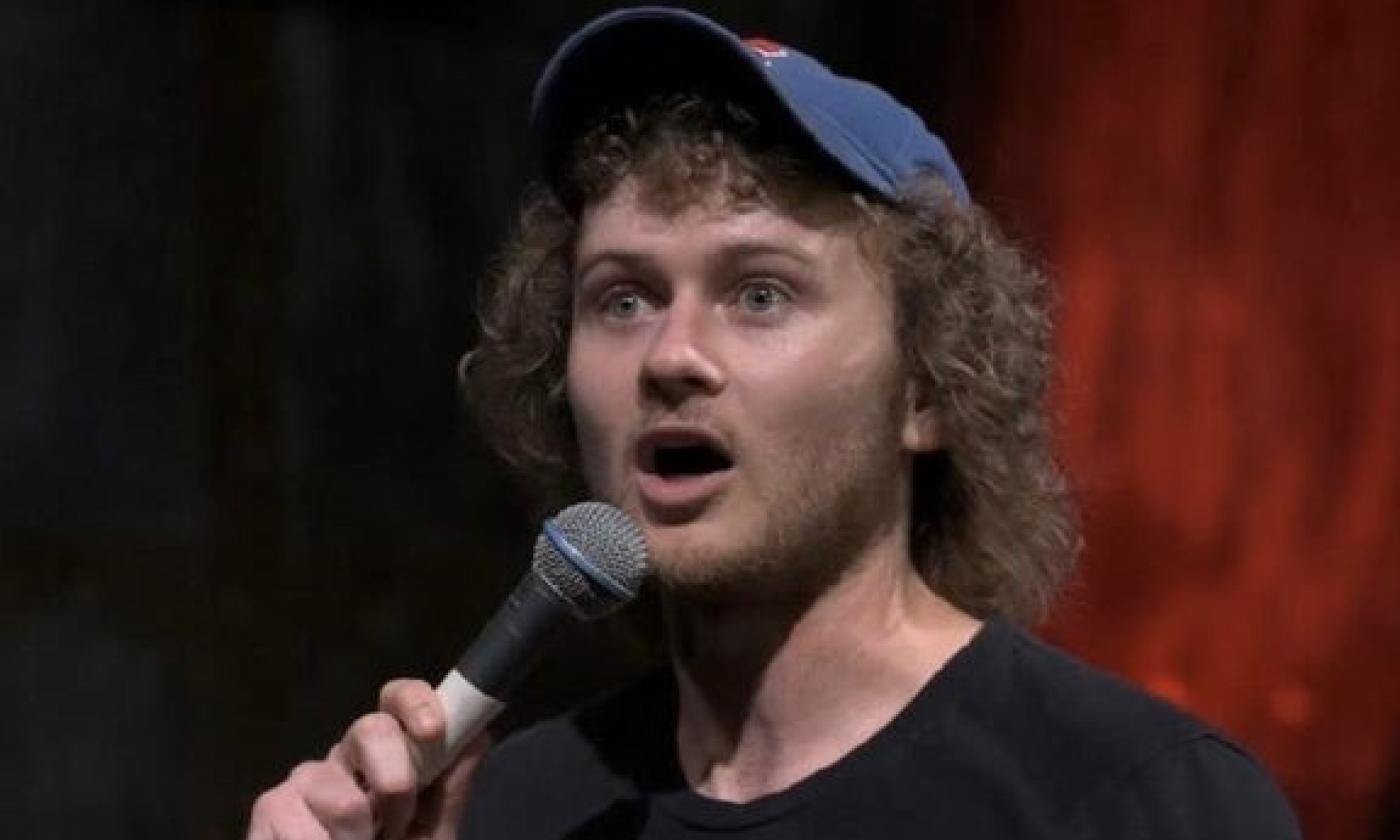 Casey Rocket speaks in front of a red and black backdrop. 