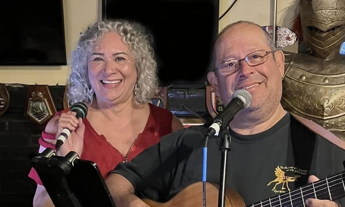 musicians Millie and Galin on stage, with microphone and guitar