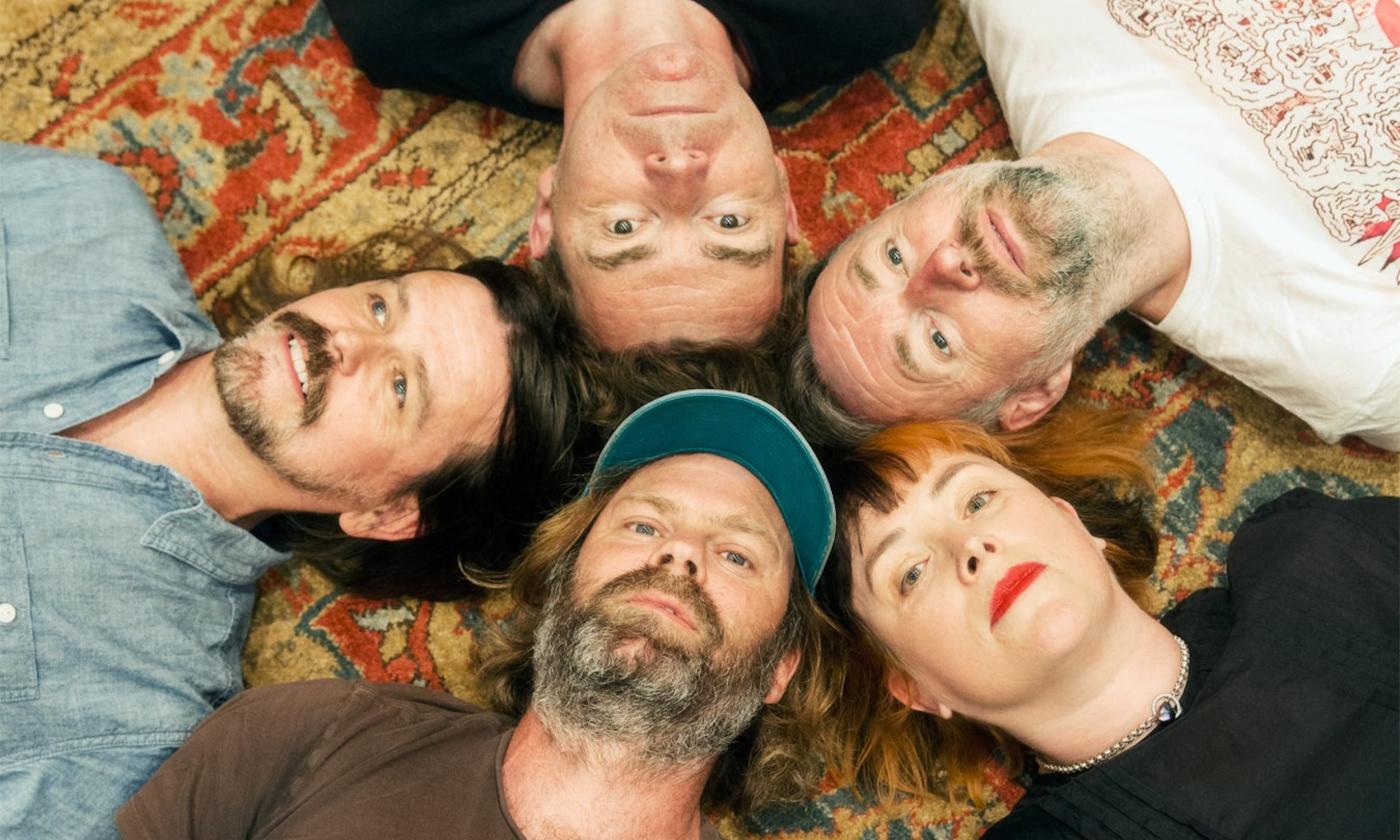 Bandmates from Slow Dive lay together on a multicolored carpet.