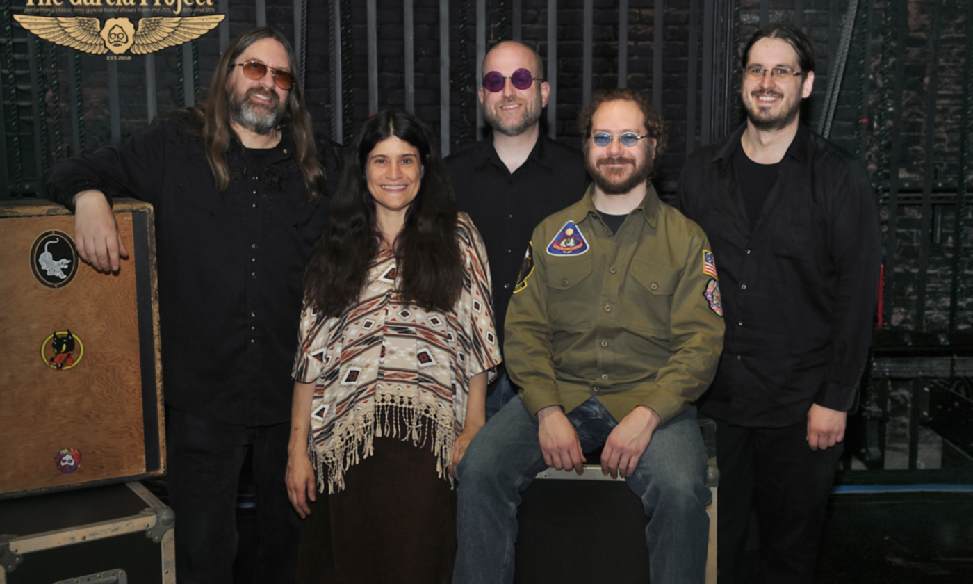 Bandmates from The Garcia Project smile and pose in front of a black backdrop. 