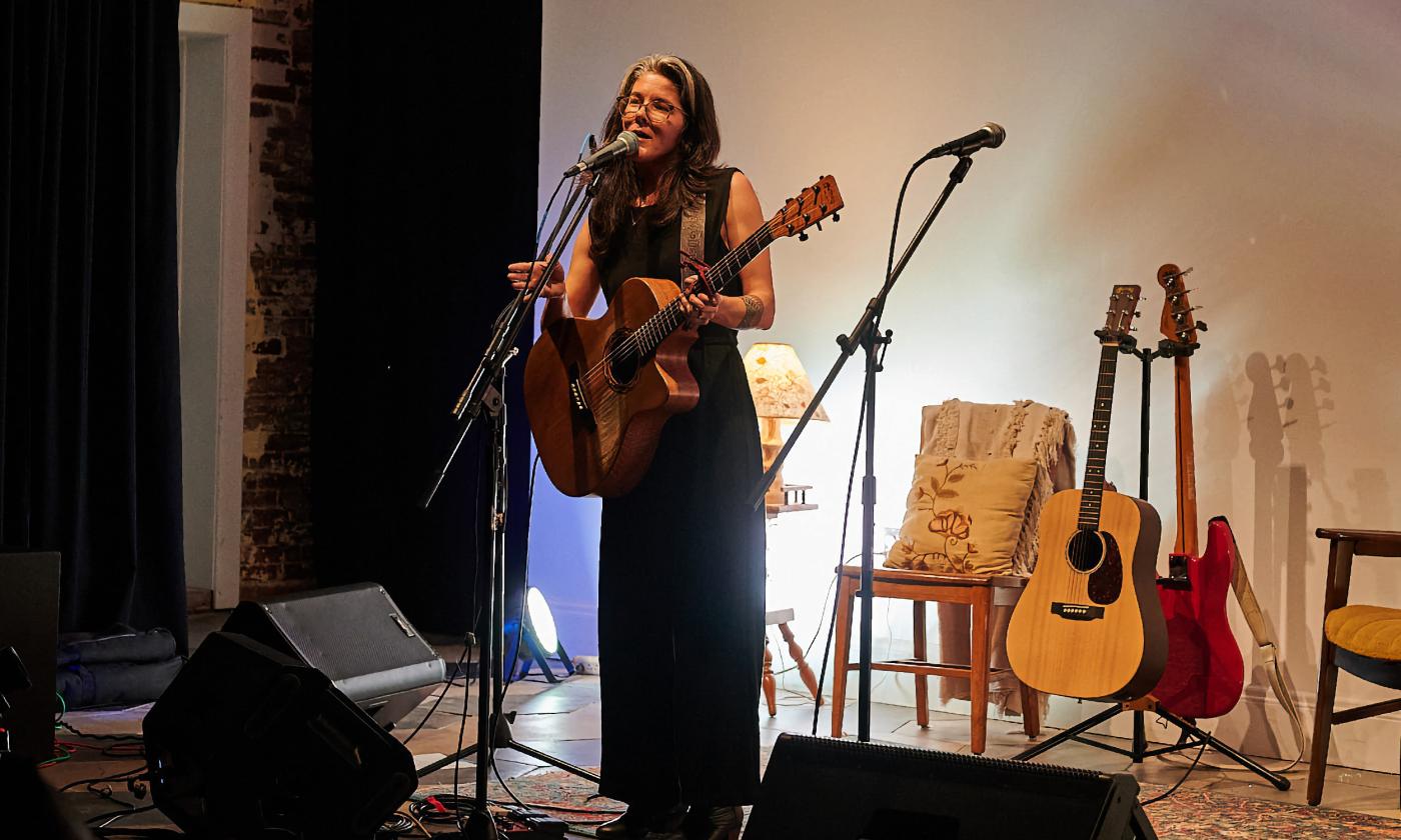 Singer and songwriter Chelsea Saddler standing on the Waterworks stage with her guitar