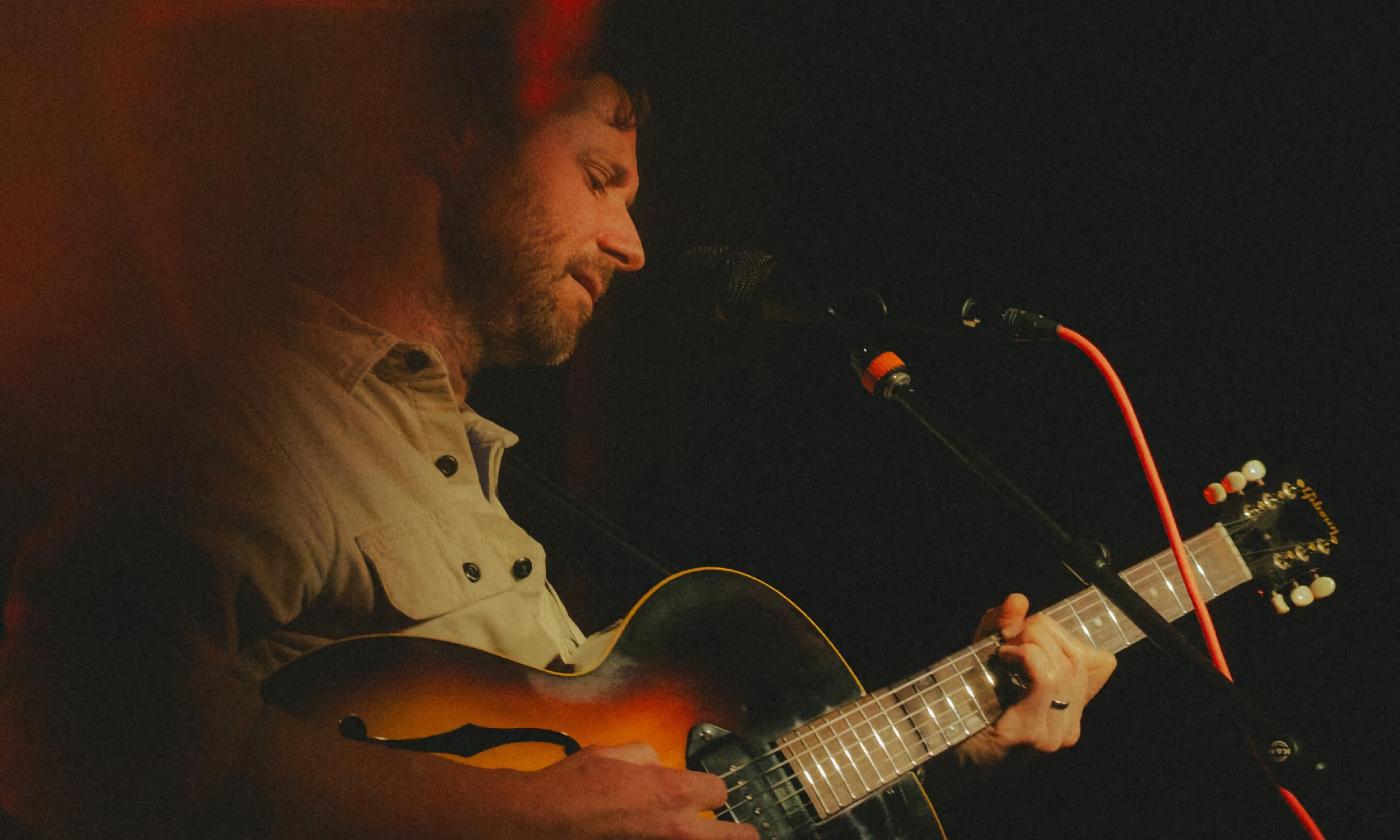 Musician Dan Mangan on stage with a guitar