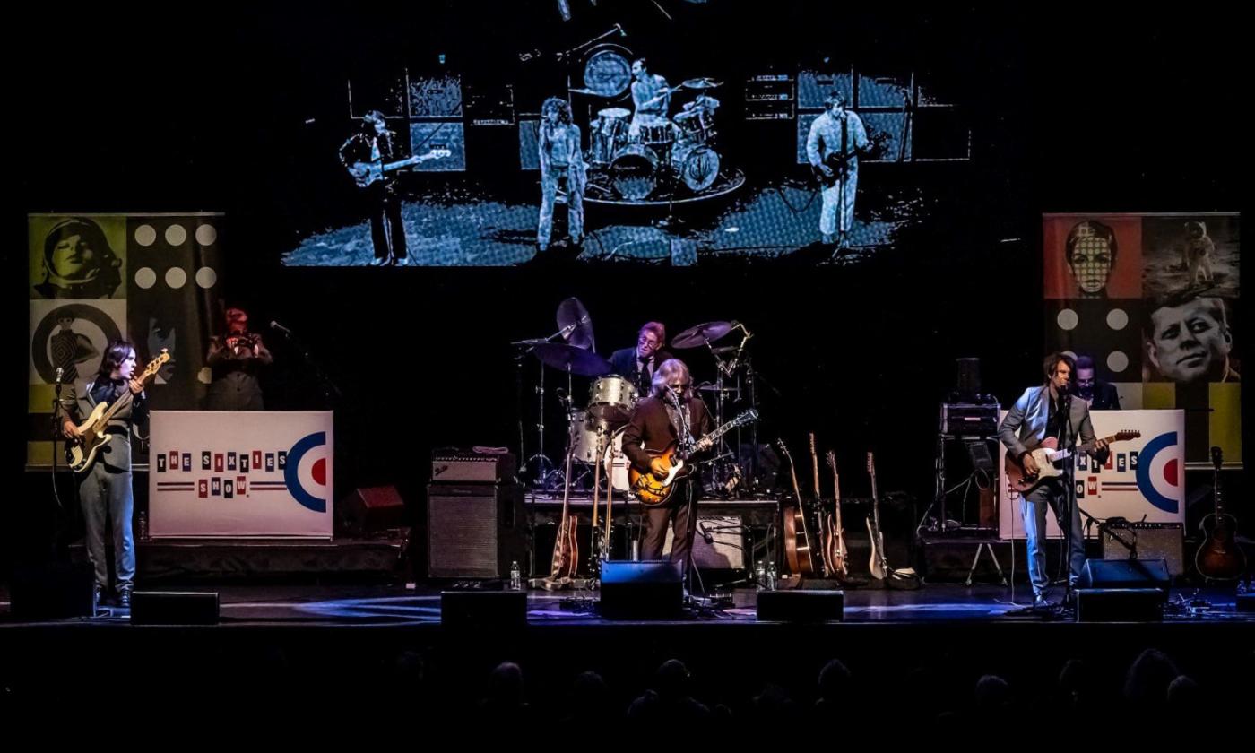 Bandmates from The Sixties Show perform live on stage.