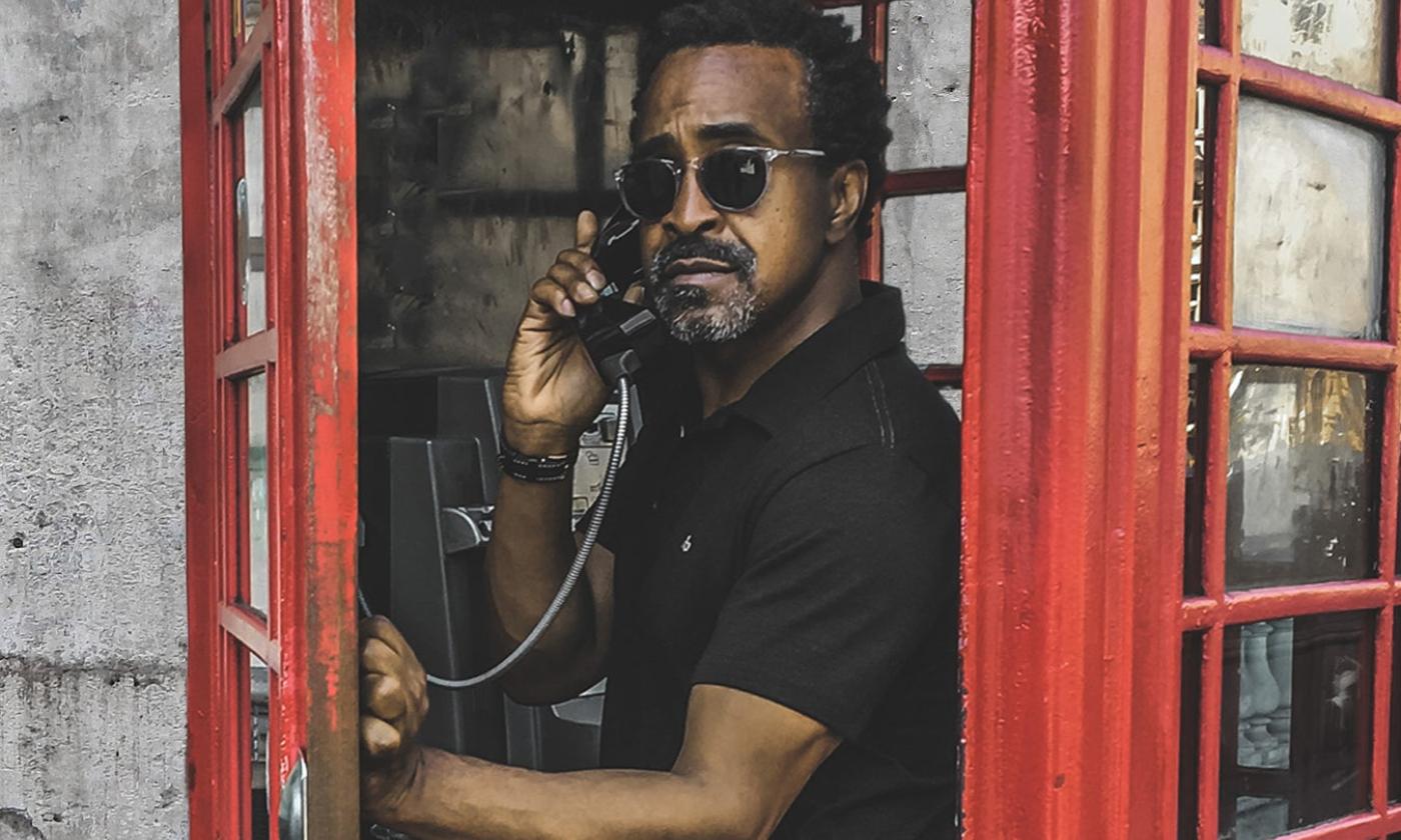 Tim Meadows stands in a phone booth and poses for fans.