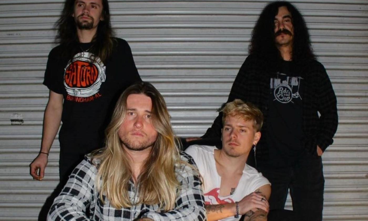 Bandmates from Versvtile pose in front of a grey backdrop.