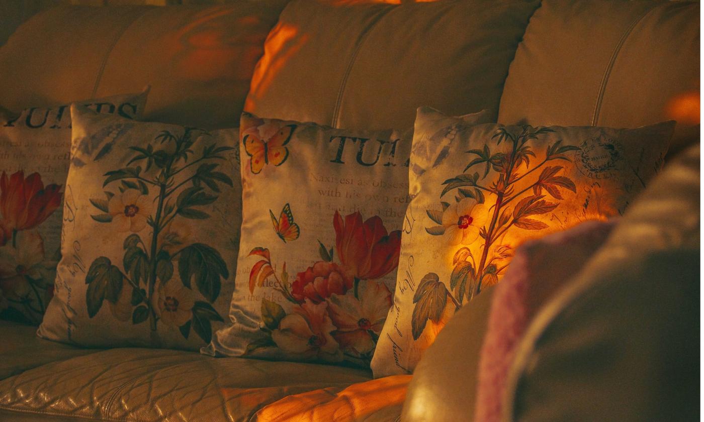 A living room sofa, covered with pillows, and lit by the sun