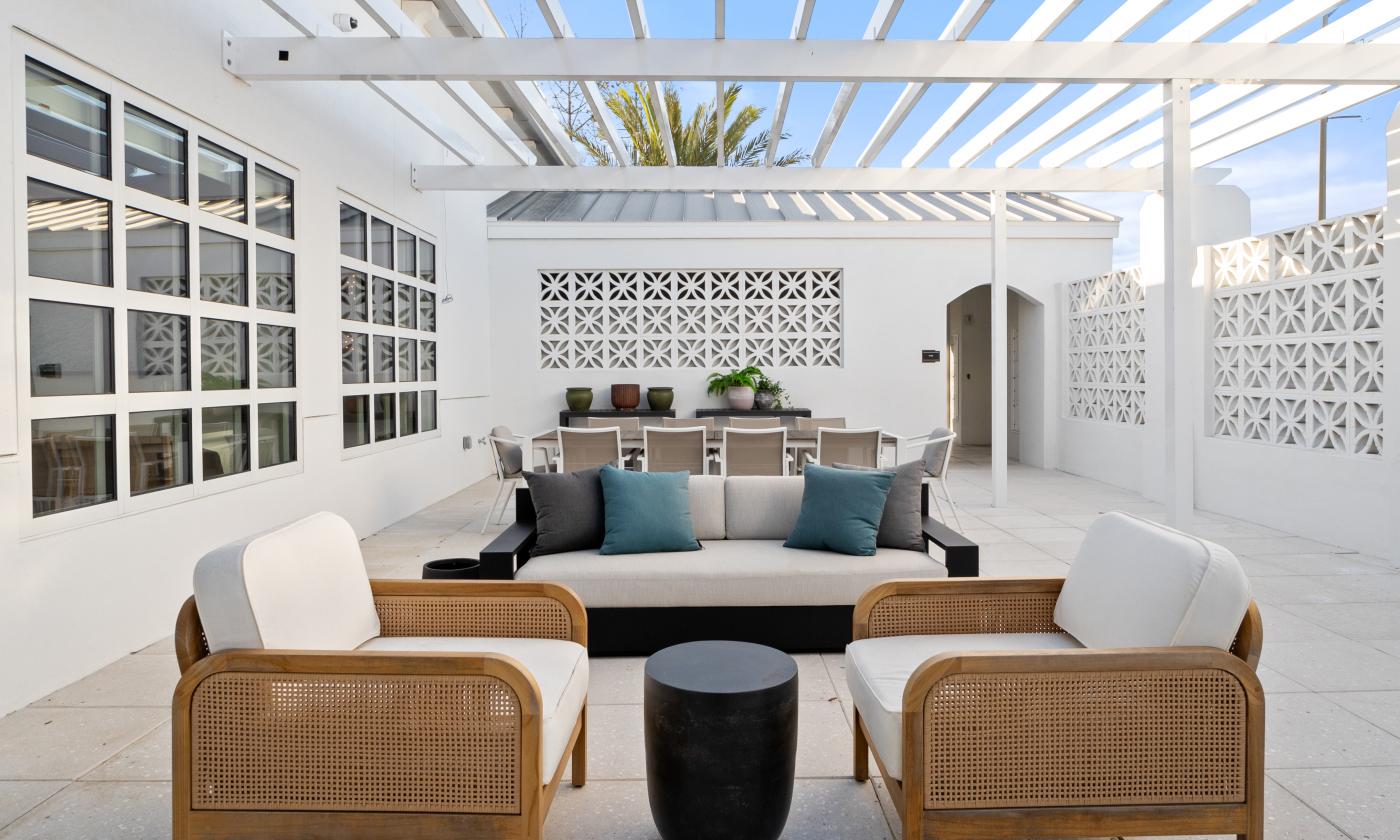 This outdoor lounge is under a pergola and offers multiple seating areas