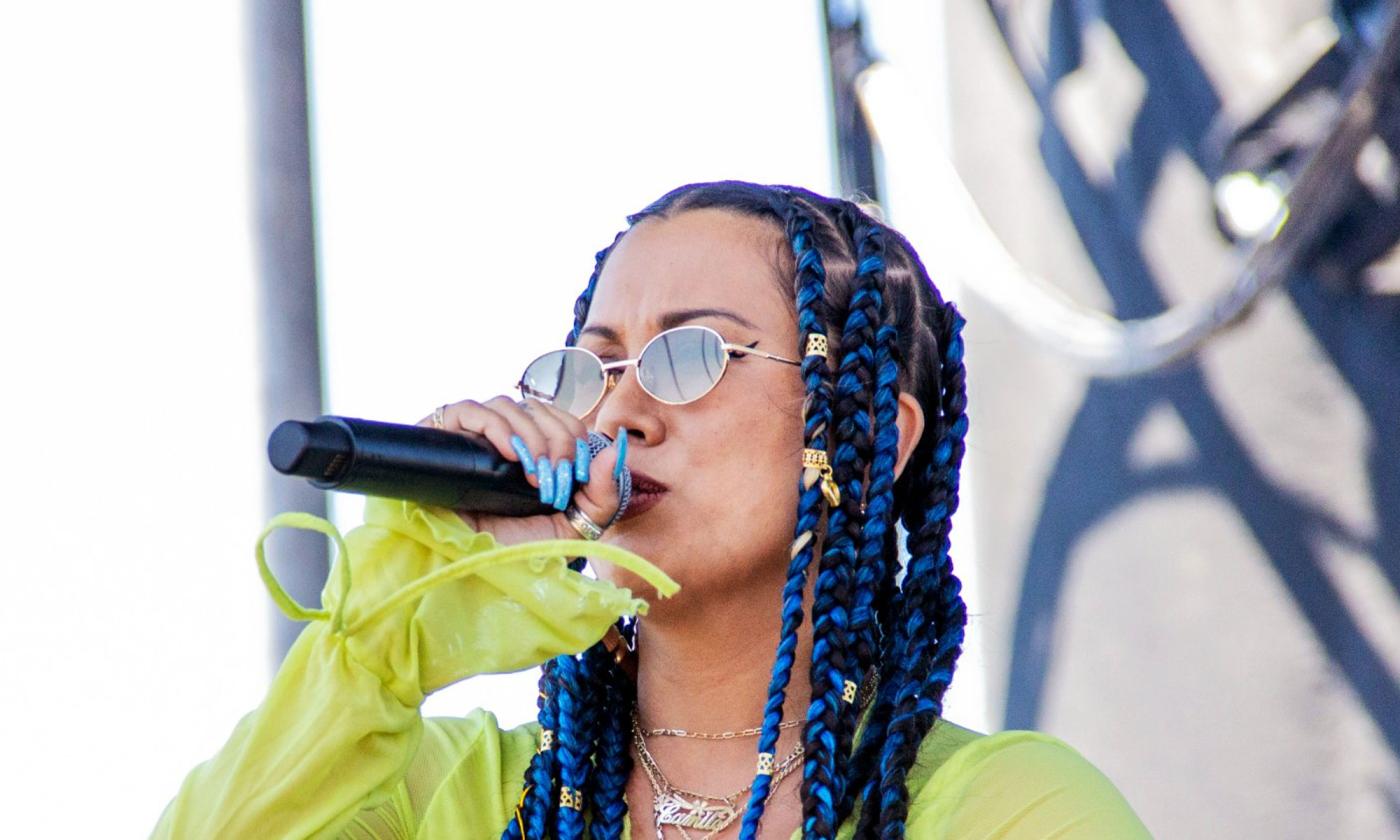 singer Eli-Mac (in sunglasses) onstage outside, holding microphone