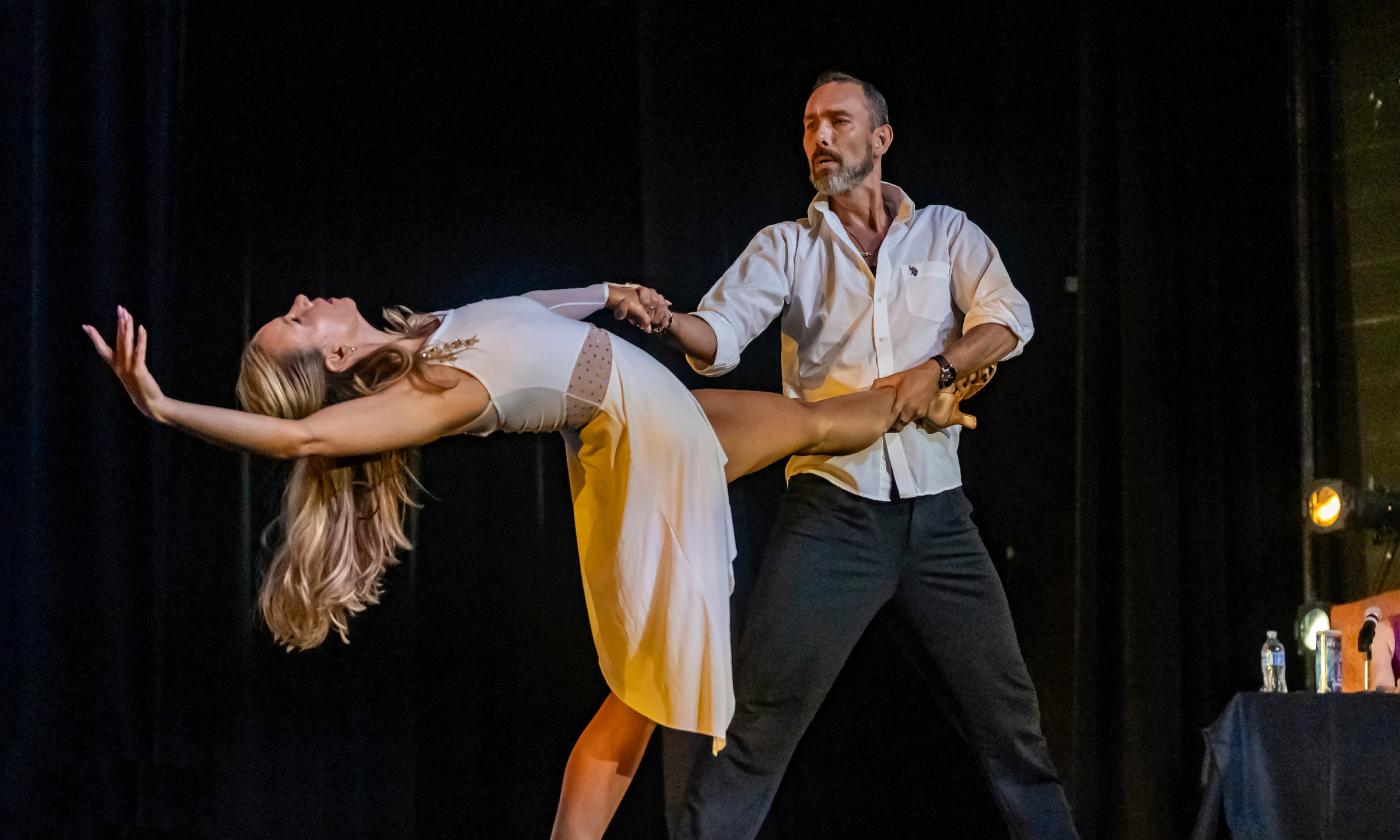 Two dancers, on a dark stage, in an elegant pose