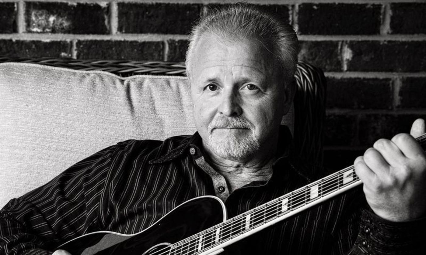 Singer songwriter Frank Myers sitting with his guitar