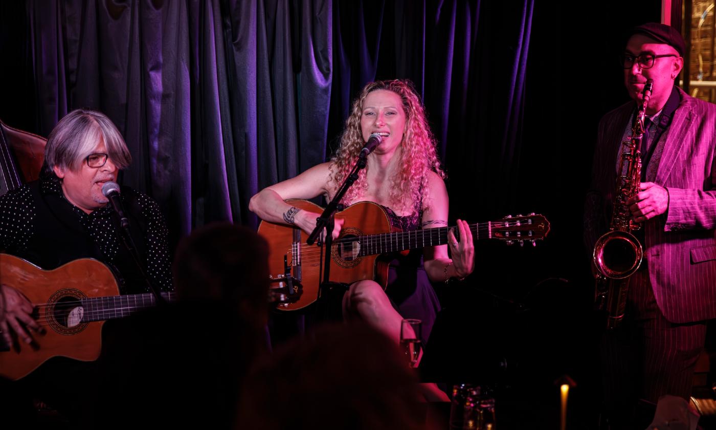 Three musicians on stage, two with guitars