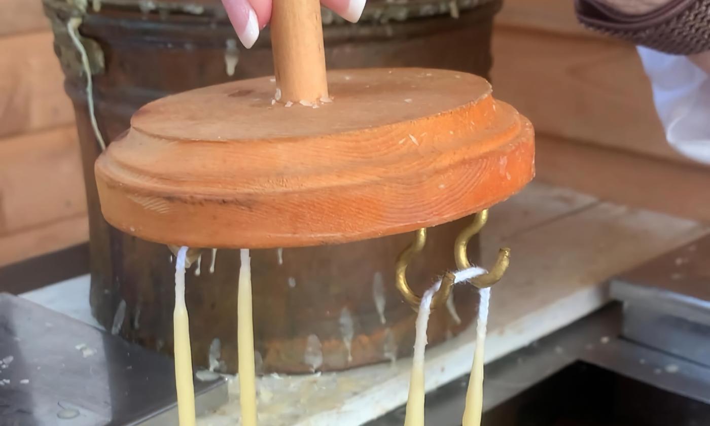 Candles hung by their wicks being dipped in beeswax