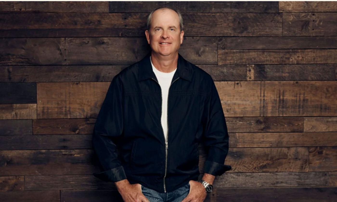 Songwriter Monty Criswell standing in front of a brown wood wall