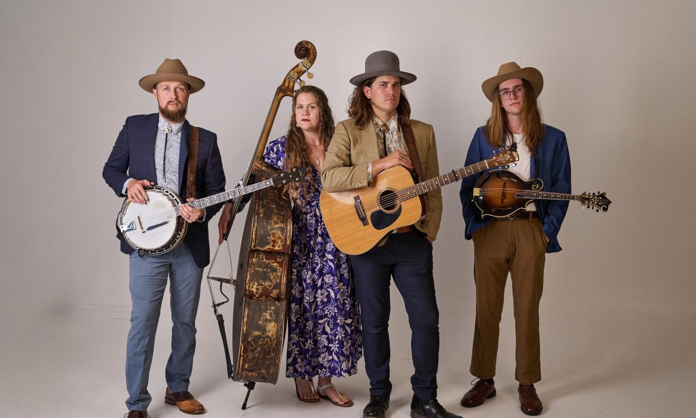 The four members of Remedy Tree, with their instruments, against a beige background
