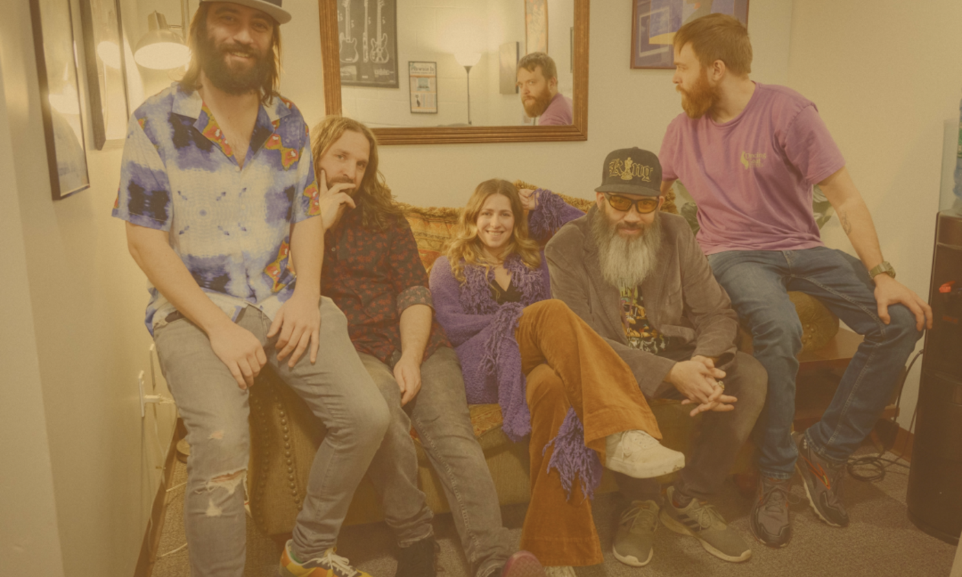 Bandmates from Bearly Dead smile and pose together in a cozy room with a mirror.