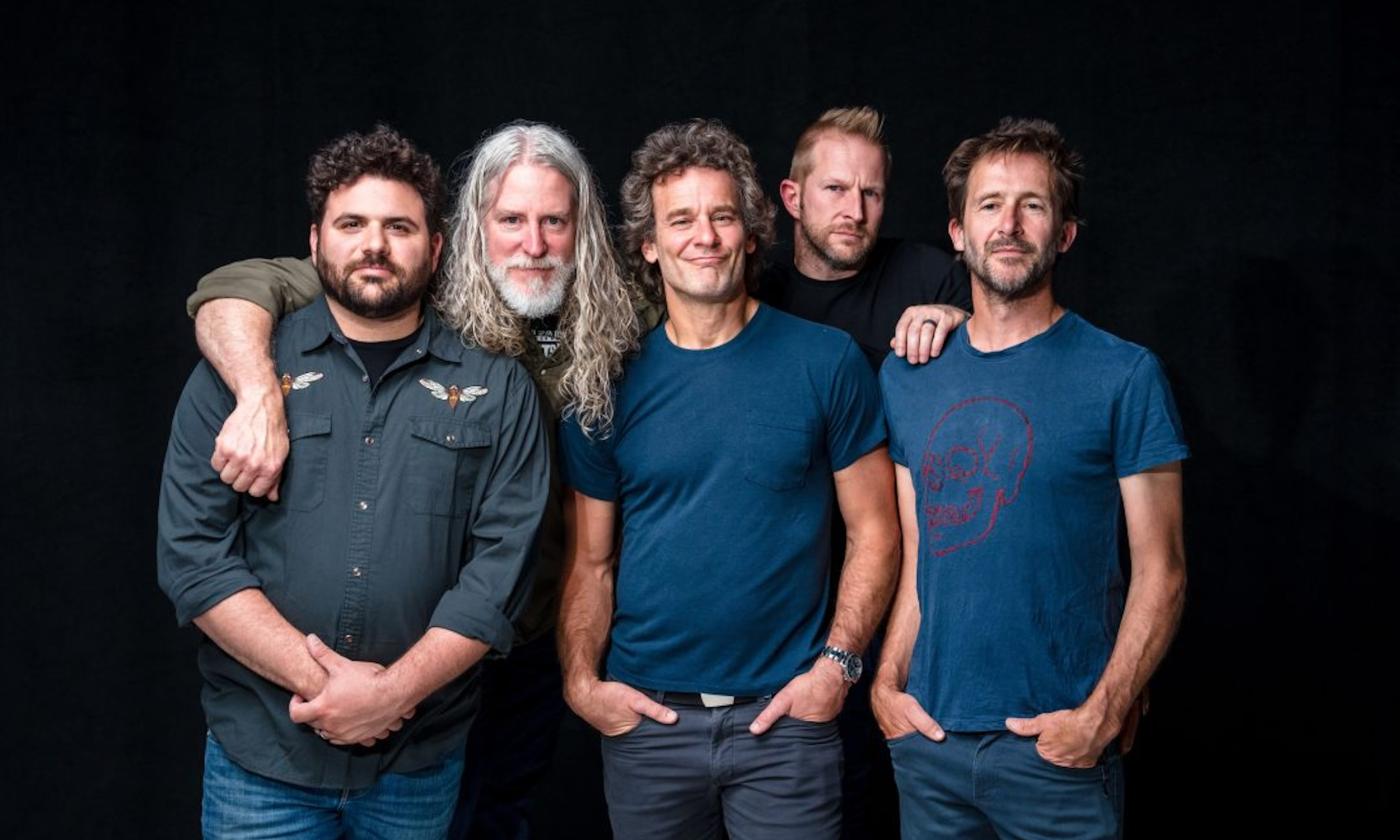 Bandmates from Carbon Leaf huddle together and pose in front of a black backdrop.