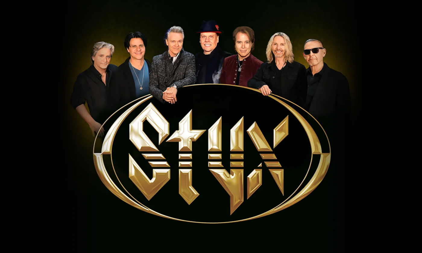 Bandmates from Styx smile and pose in front of a black backdrop.