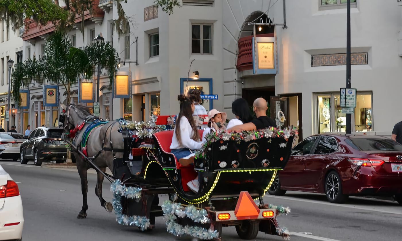 A horse-drawn carriage traveling along Kind Street at dusk during Nights of Lights