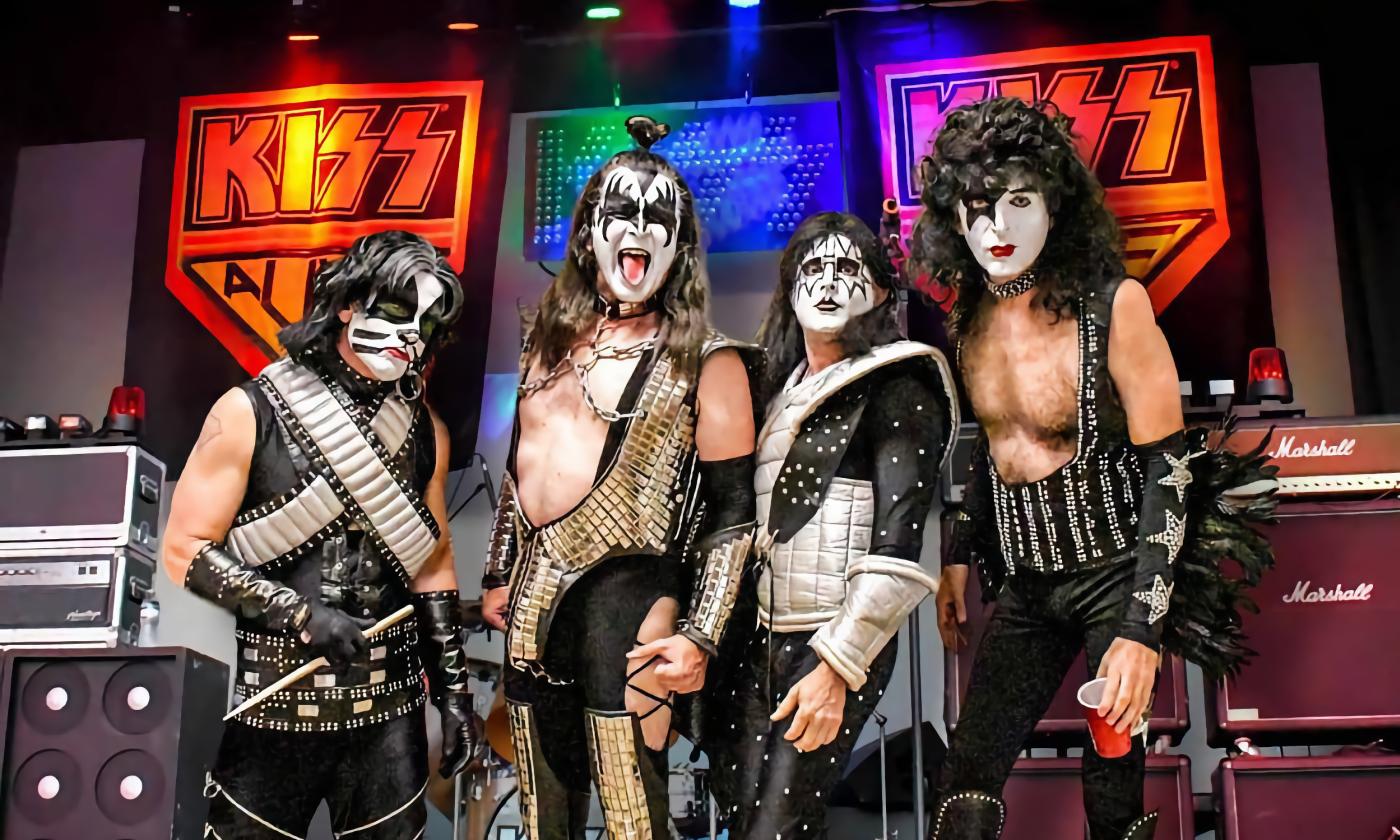 Members of Kiss Alive the Tribute standing next to gear on stage